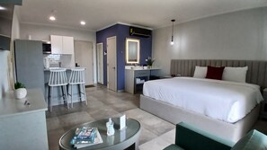 Une chambre d’hôtel moderne comprenant un lit, un petit coin salon, une kitchenette et une salle de bain.