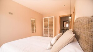 Quarto com uma cama grande, um guarda-roupa e um espelho.