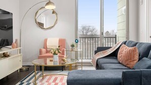 A modern living room with a sofa, armchair, coffee table, and a large mirror. - Stylish 2BR Suite Near DT Traverse City + Smart TV (Traverse City)