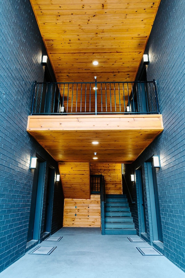 Stunning staircase and balcony overlook a spacious interior with a light-colored floor.