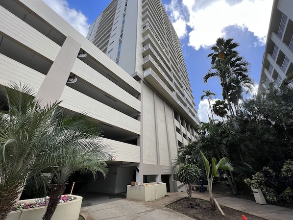 A multi-story parking garage with a modern design, surrounded by palm trees and concrete planters.