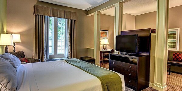 A hotel room with a large bed, a television, a desk, and a chair.