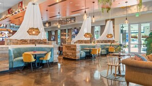 A modern hotel lobby with seating areas, a reception desk, and a large window providing a view of the outside. - Family friendly! Heated pool/free parking/tennis.  (Destin)