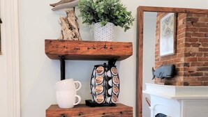 A kitchen with a coffee maker, a mug, a fish-shaped container, and a potted plant on a wooden shelf. - The Kelley House | Suite 2 - 1st floor (Pensacola)