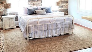 A bedroom with a bed, two nightstands, a ceiling fan, and a large window. - The Kelley House | Suite 3 w/Balcony (Pensacola)