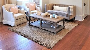 Un salon avec un lustre, deux canapés, une table basse et un tableau encadré accroché au mur.