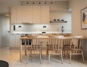 A modern kitchen with a central island, wooden chairs, and pendant lighting.