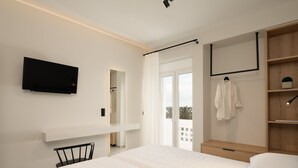 Ein modernes Schlafzimmer mit Bett, Wand-Fernseher, Holzschrank und Balkon mit Blick.