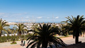 A marina with boats, palm trees, and a clear sky.