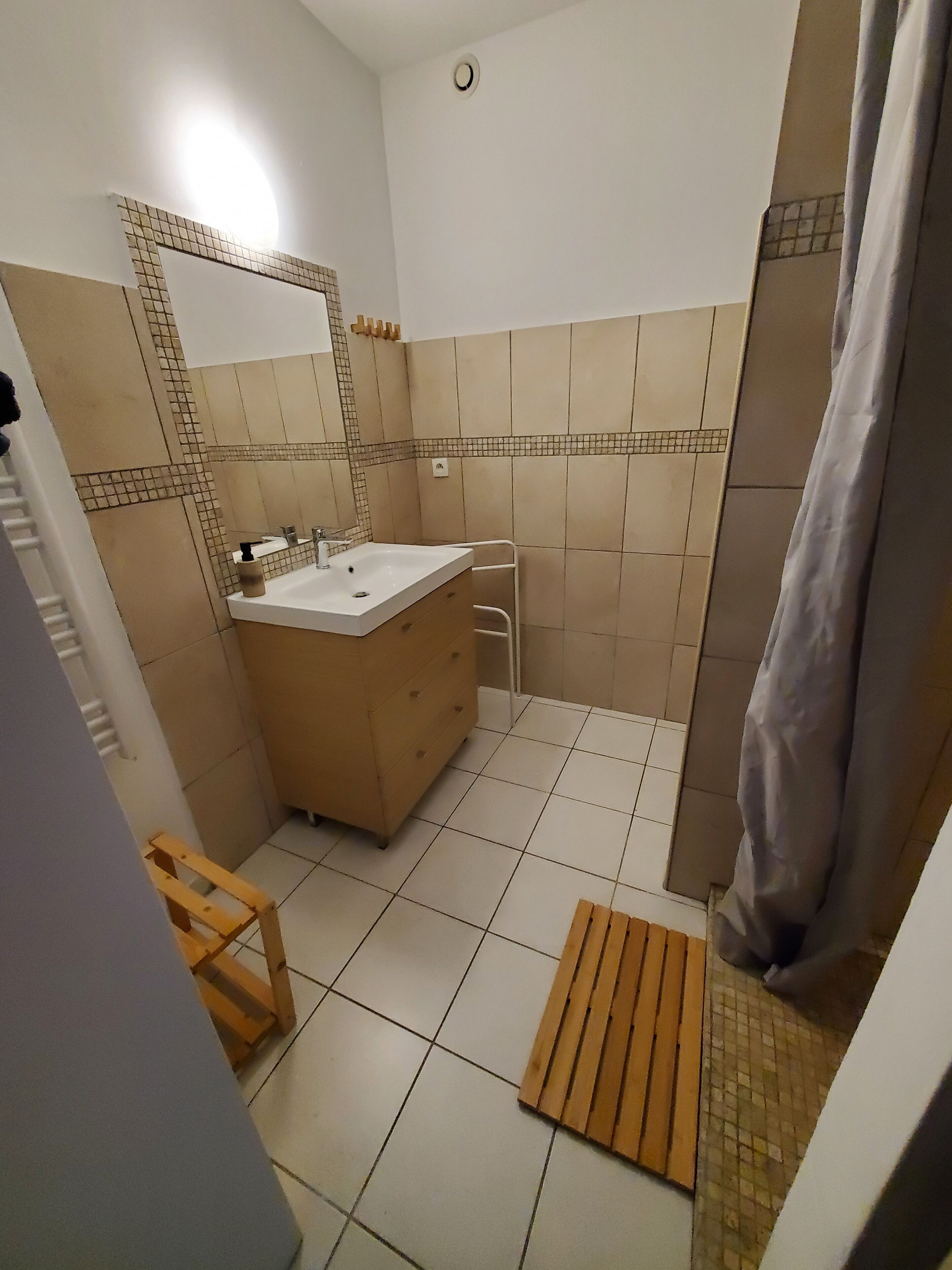 A bathroom with a sink, mirror, and tiled walls.