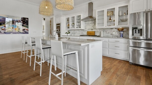 A modern kitchen with white cabinetry, stainless steel appliances, and a central island with bar stools. - Heated Pool, Steps to Beach, Stylish Interior, Amenities Galore!  (Waveland)