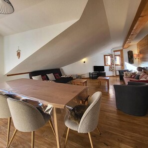A spacious loft-style living area with a high ceiling, wooden flooring, and a mix of modern and traditional furnishings.