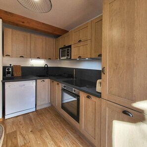 A compact kitchen with wooden cabinets, a microwave, a dishwasher, and a stove.