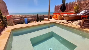 Relax by the ocean with a serene pool surrounded by lounge chairs and lush greenery.