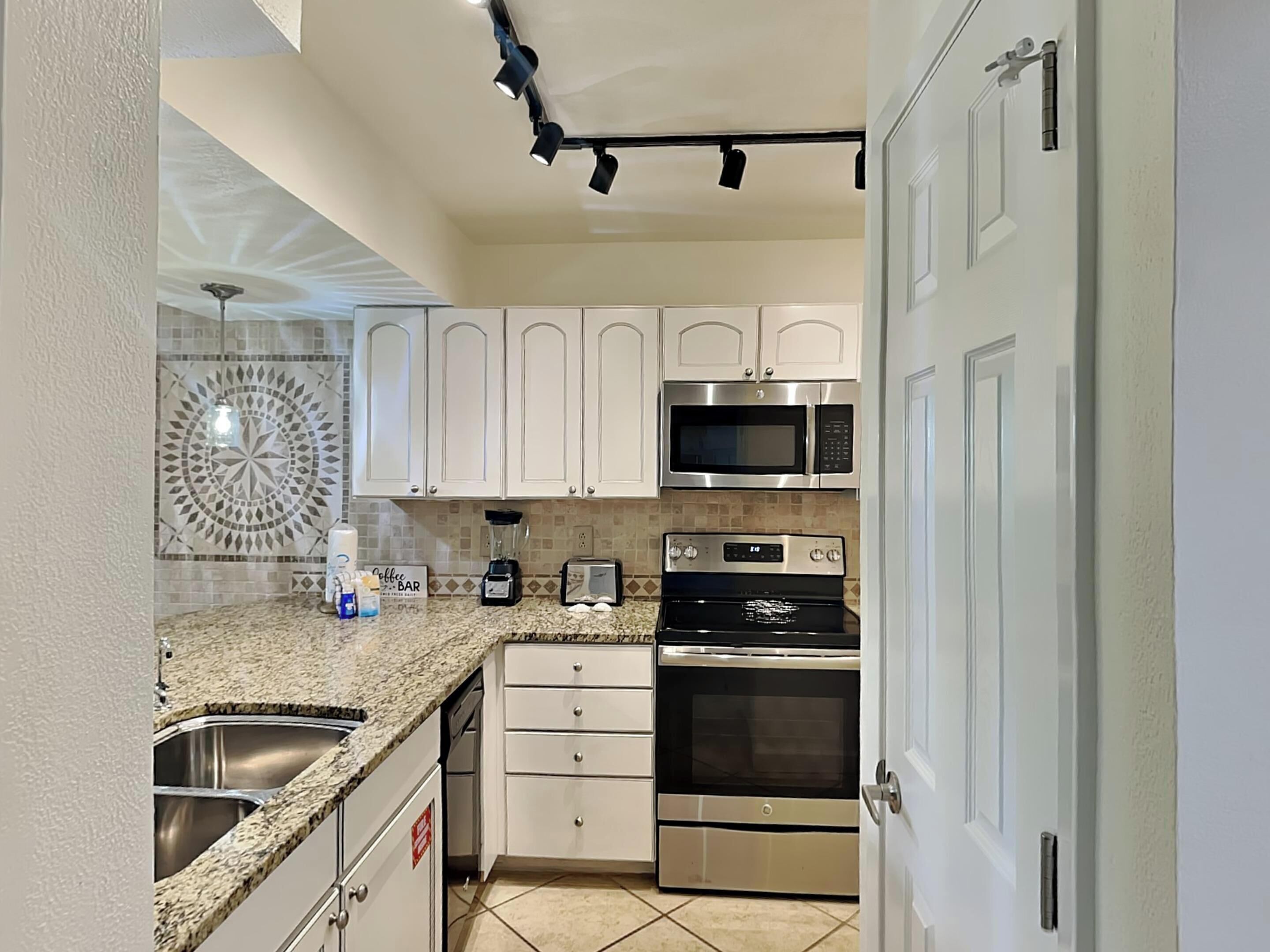 A modern kitchen with white cabinets, stainless steel appliances, and a granite countertop.