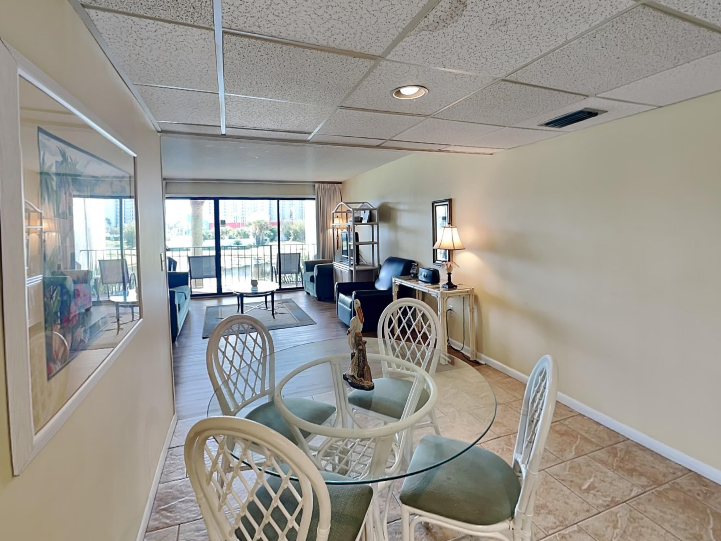 A hotel room with a balcony, a dining area with a table and chairs, and a TV.