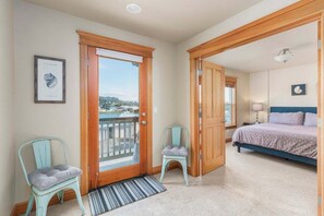 Un dormitorio con cama, una puerta que da a un balcón y dos sillones.