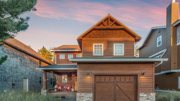 A two-story house with a prominent garage, a covered porch, and a stone foundation. - Sea Jay-hot tub, 2 blocks to beach, borders forest (Pacific City)