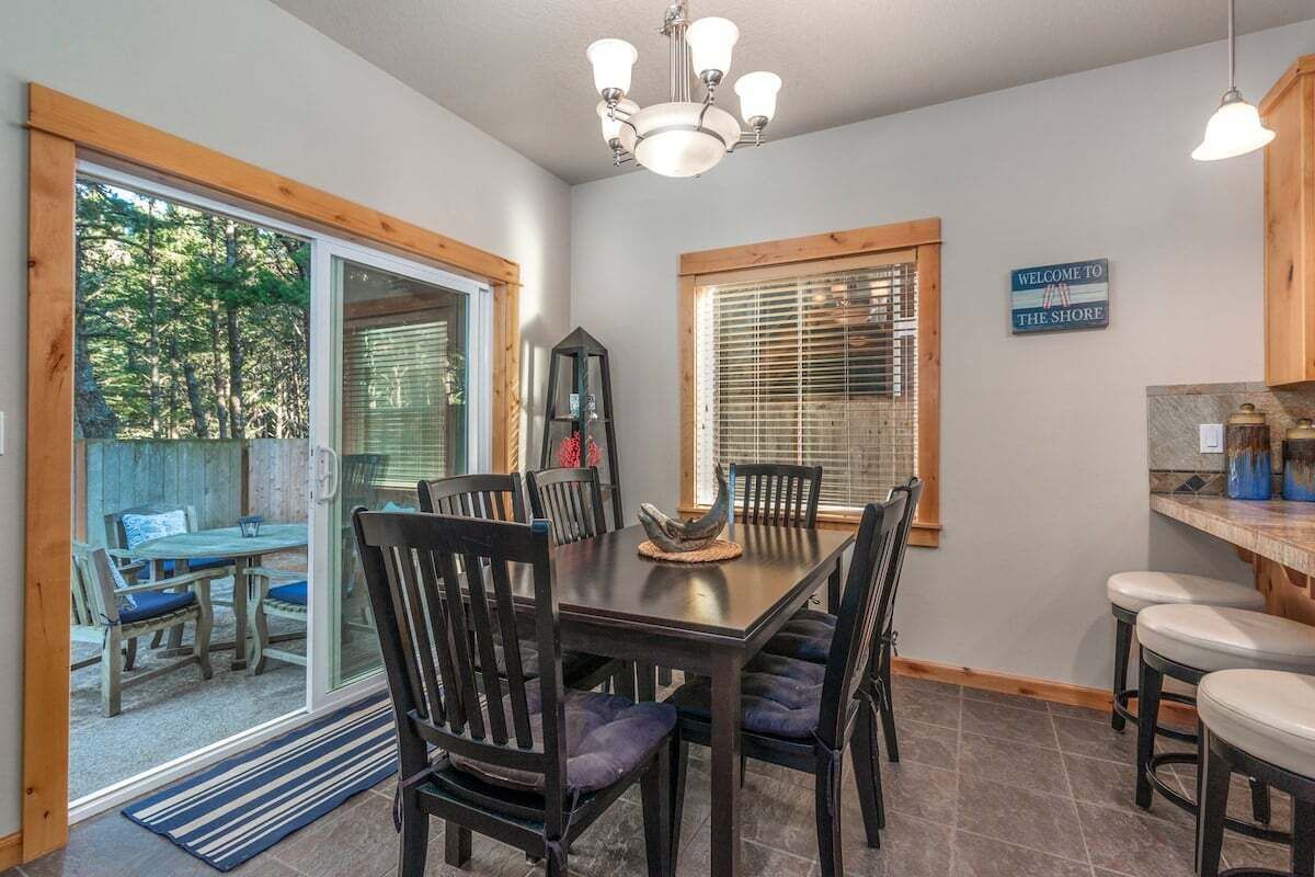 A dining area with a table and chairs, a chandelier, and a sign that reads "WELCOME TO THE SHORE".