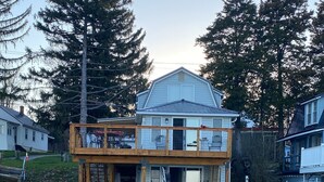 Une propriété située au bord de l’eau, avec une jetée en bois menant à une maison dotée d’un balcon.