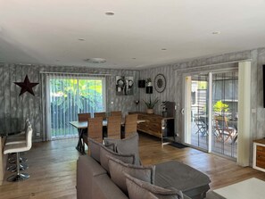 Un vaste espace de vie comprenant un grand canapé, une table à manger et des chaises, une décoration en forme d’étoile et une vue à travers la porte-fenêtre coulissante.