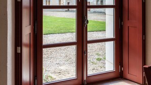 Un conjunto de puertas dobles de madera con un ventanal semicircular, que dan a un patio con un edificio al fondo.