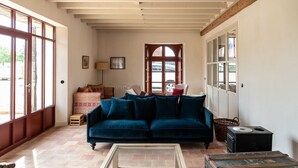 Una sala acogedora con un sofá azul, una mesa de centro de vidrio y un cofre de madera rústica.