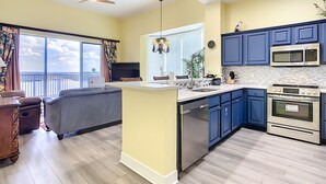 A modern kitchen with blue cabinets, stainless steel appliances, and a large island.