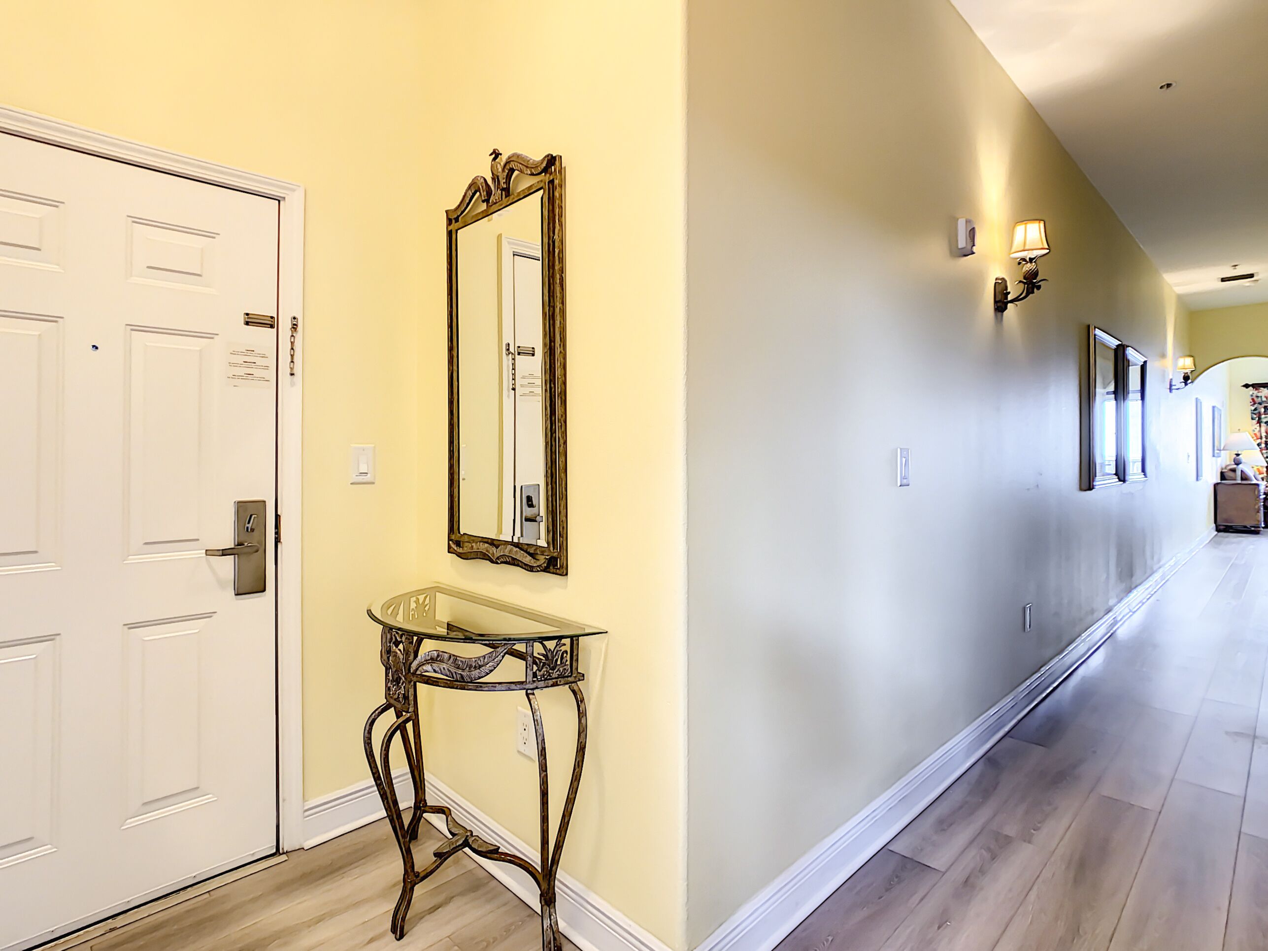 Un couloir avec une porte blanche, un miroir et une petite table.