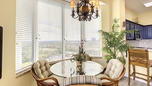 A dining area with a round table, wicker chairs, and a chandelier.