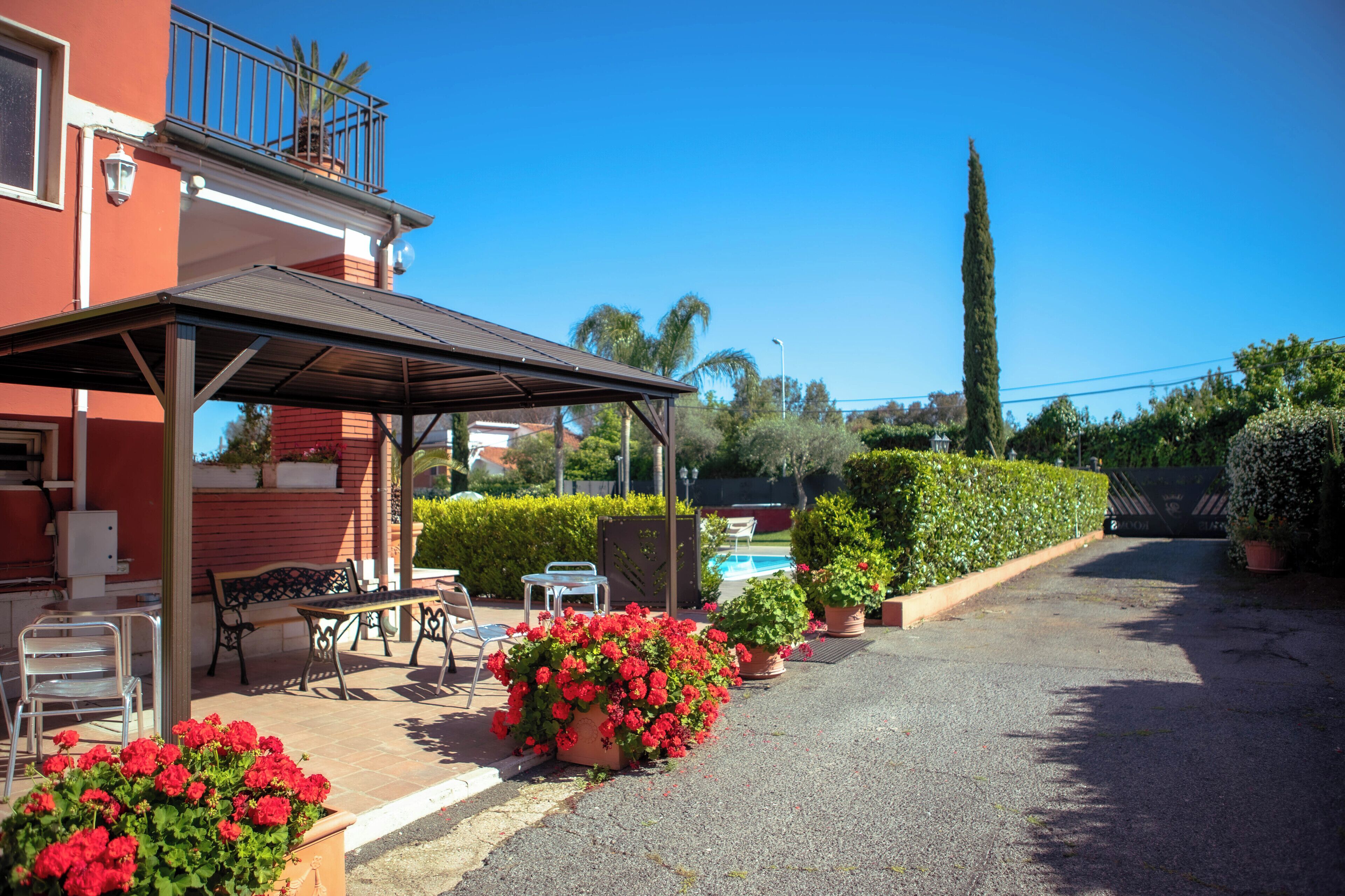 A covered outdoor seating area with a pool in the background.