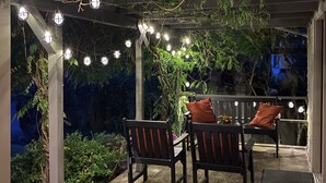 An outdoor patio area with wooden chairs and tables, string lights, and greenery. - Welcome to Bungalow 437! Close to Downtown & OSU!  (Corvallis)