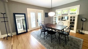 A dining area with a wooden table and chairs, a rug, and a ceiling light fixture. - Welcome to Bungalow 437! Close to Downtown & OSU!  (Corvallis)