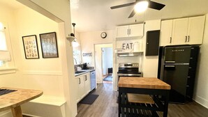 A modern kitchen with white cabinets, a black refrigerator, and a wooden dining table. - Welcome to Bungalow 437! Close to Downtown & OSU!  (Corvallis)