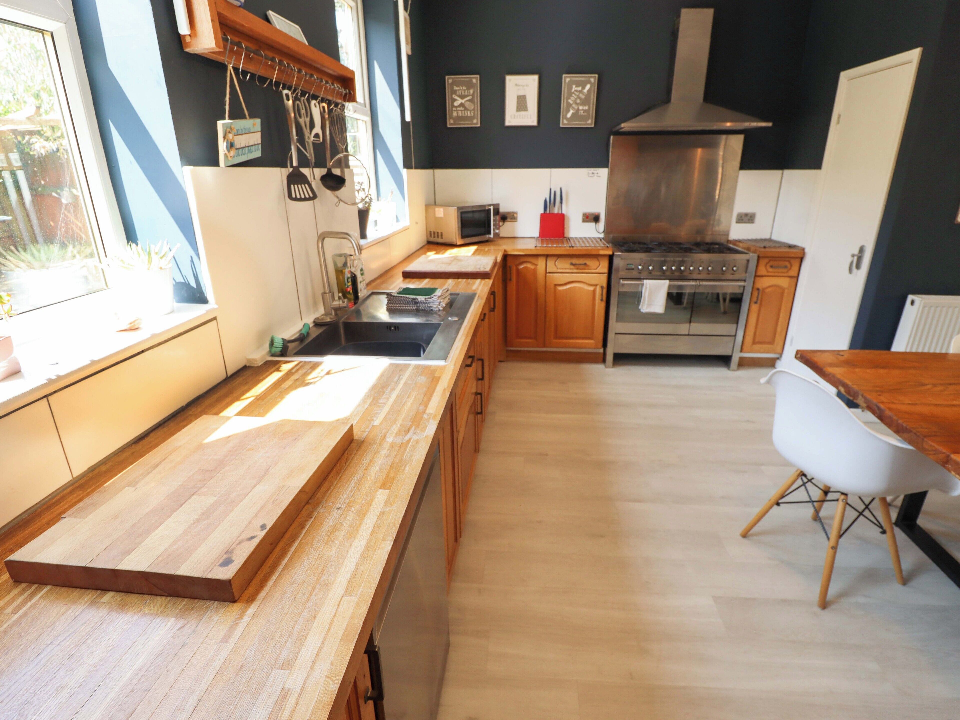 A modern kitchen with wooden countertops, a stainless steel stove, and wooden cabinets.