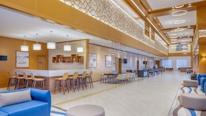 Een ruime lobby met een receptiebalie, zithoeken en een modern design.