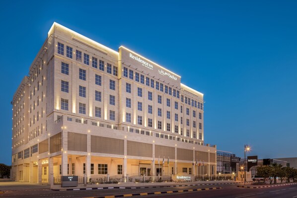 Un hotel de varios pisos con un llamativo letrero de "Residence Inn", que presenta un estilo arquitectónico clásico con techo plano y ventanas simétricas.