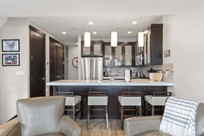 A modern kitchen with dark cabinets, a central island, and pendant lighting.