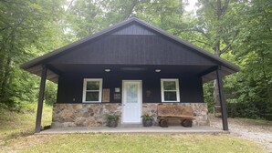A rustic cabin with a stone foundation and a dark wooden exterior. - Charming Secluded Getaway Cabin within minutes of amenities  (Cape girardeau)