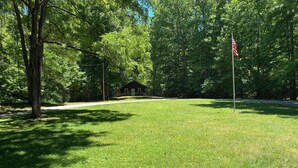 A grassy area with a small building and a flagpole. - Charming Secluded Getaway Cabin within minutes of amenities  (Cape girardeau)