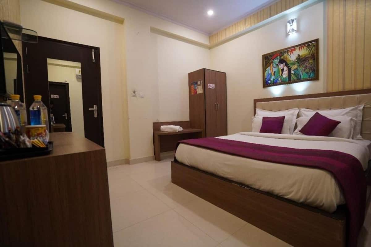 A hotel room with a bed, a wardrobe, a nightstand, and a mirror.