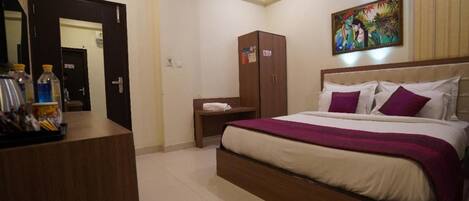 A hotel room with a bed, a wardrobe, a nightstand, and a mirror.
