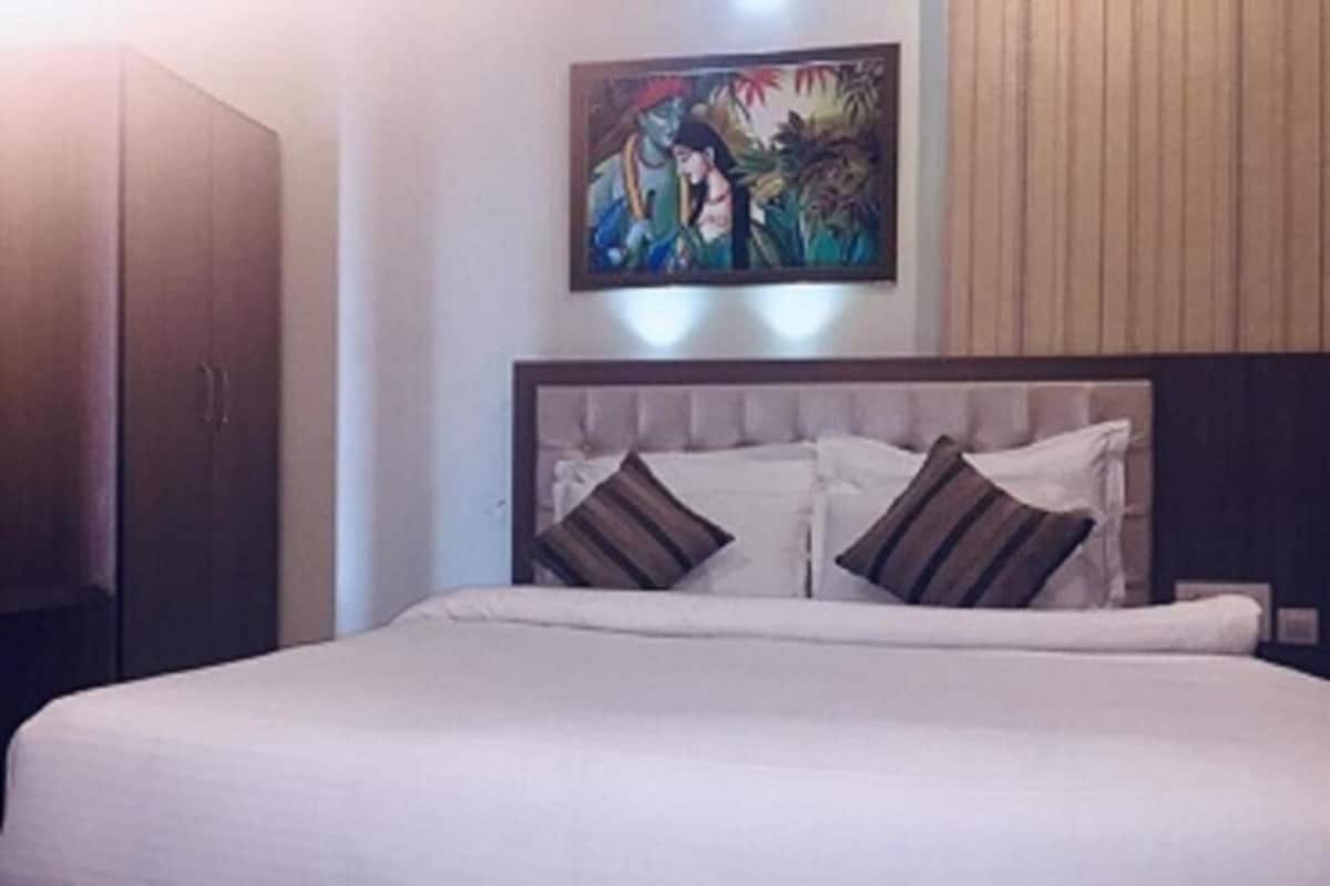 A bed with a headboard, pillows, and a painting on the wall.