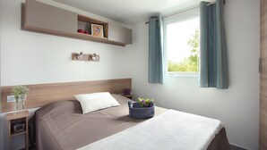 A bedroom with a bed, bedside table, and a window with curtains.