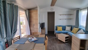 A modern, well-lit room with a dining table, chairs, a sofa, and a TV.