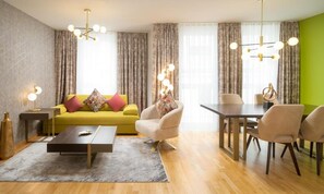Un salon moderne avec un canapé jaune, une table basse et un coin repas comprenant une table et des chaises.