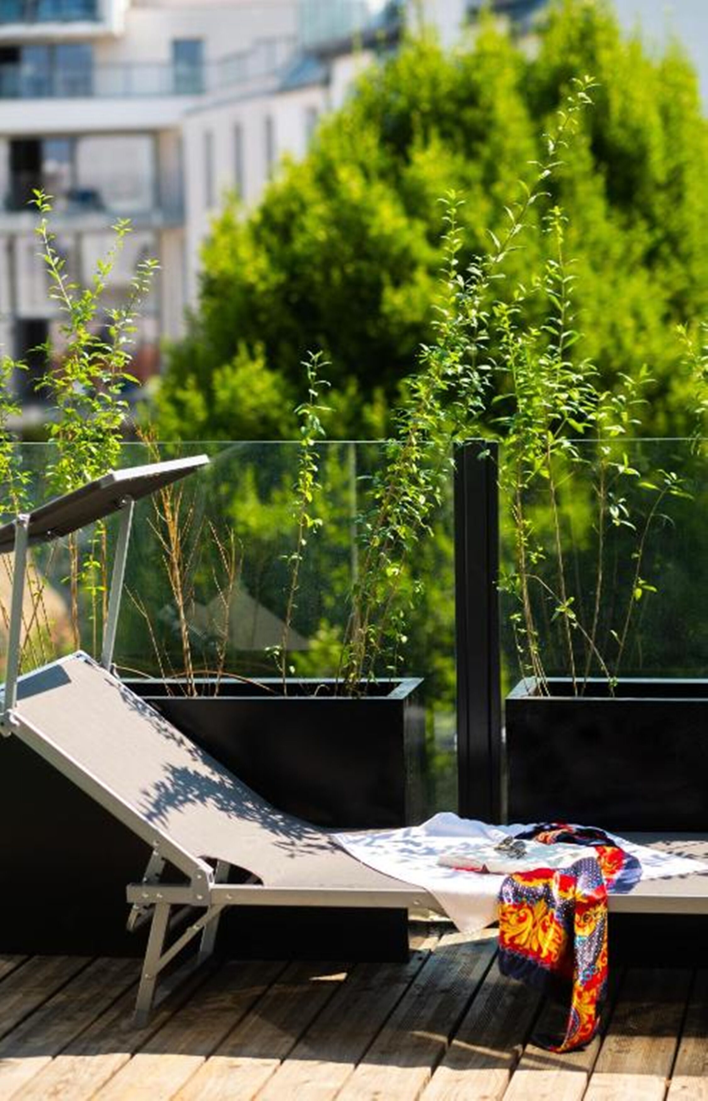 Eine Dachterrasse mit Liegestuhl, kleinem Tisch und einer bunten Tasche.
