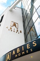 Un edificio moderno con el letrero "ABIES HOMES" en la fachada.