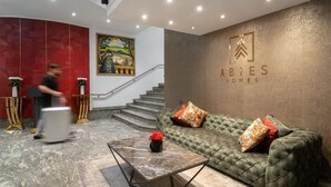 Un hall con un sofá verde, una mesa de centro de mármol y una escalera.