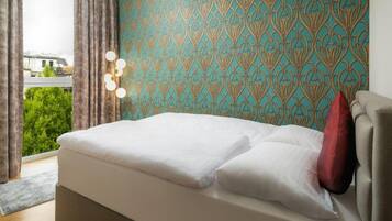 A bedroom with a bed, a patterned wall, and a view of greenery outside.